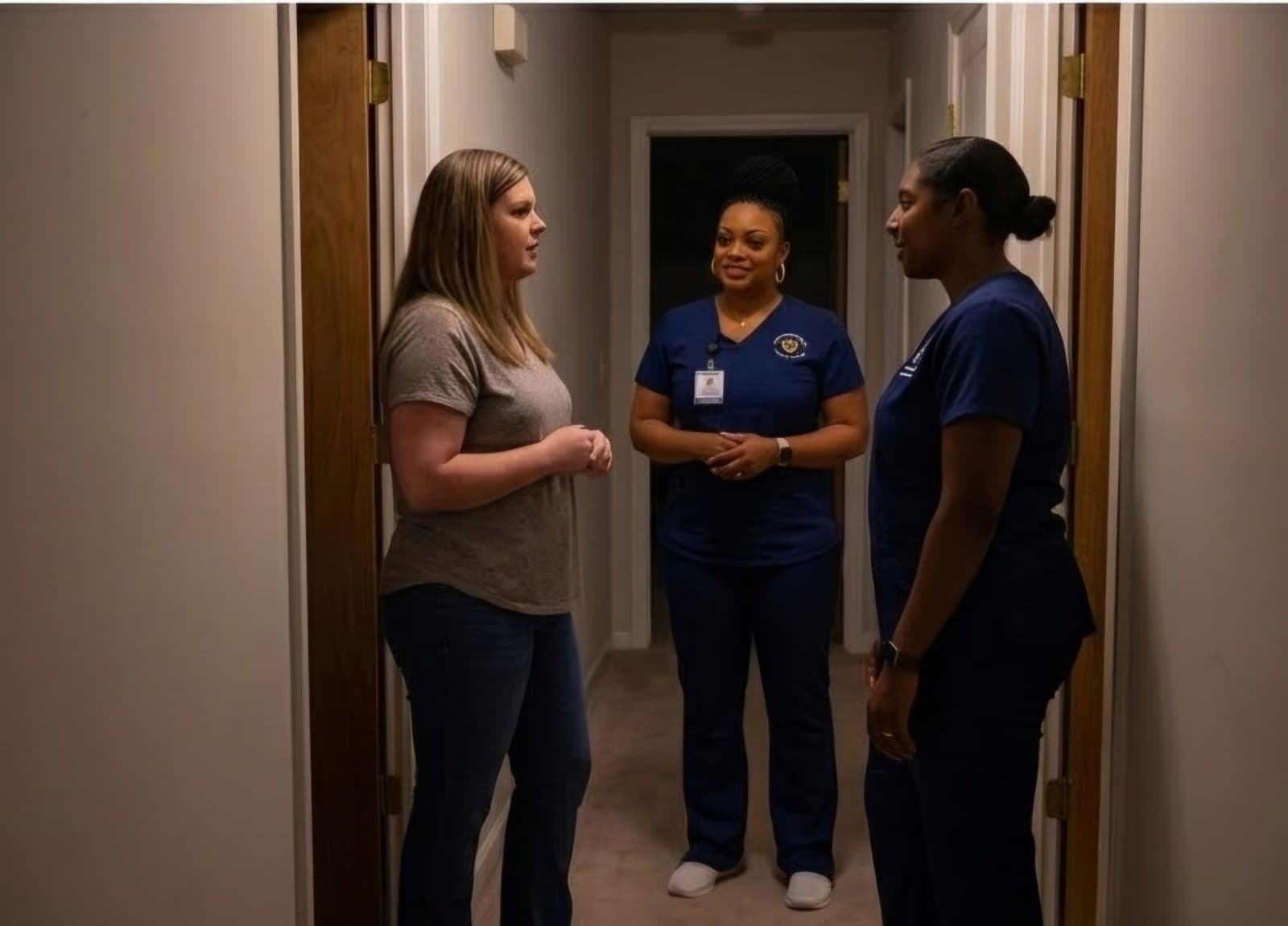 A family member talking with two Guardian Care caregivers at the door in the evening
